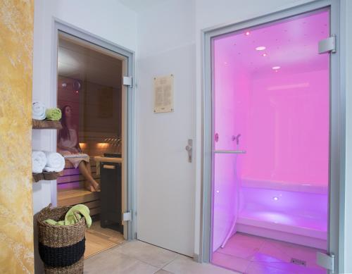 ein Bad mit einer rosa Tür, die zu einer Badewanne führt in der Unterkunft Hotel Laserz in Lienz