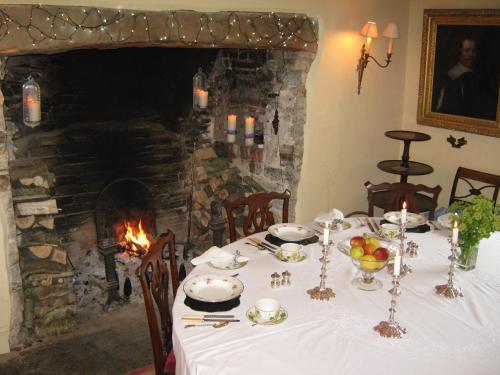 Hollamoor Farm في بارنستابل: غرفة طعام مع طاولة ومدفأة