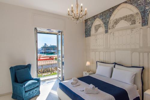 sypialnia z łóżkiem, krzesłem i oknem w obiekcie Relais Mareluna - Luxury Apartments w mieście Salerno