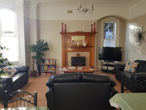 a living room with leather couches and a tv at Ivanhoe Guest House in Bridlington