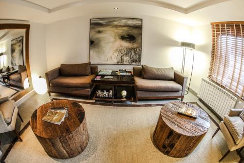 a living room with a couch and two wooden tables at Hotel Martín Gusinde in Puerto Natales