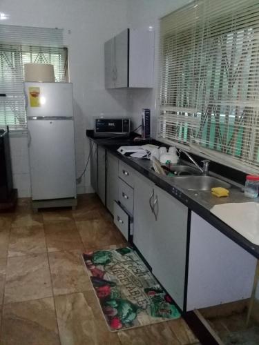 a kitchen with a white refrigerator and a sink at 3A's Guest House in Oko Sombo