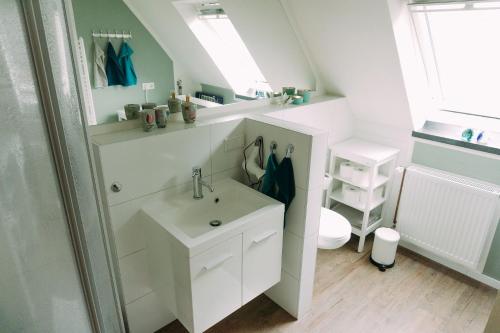 Baño blanco con lavabo y espejo en Ferienwohnung Worpsweder Schlösschen, en Worpswede