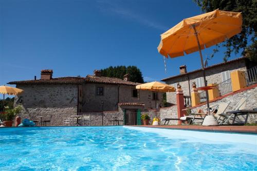 a swimming pool with an umbrella and a house at Agriturismo I Cerretelli in Barga