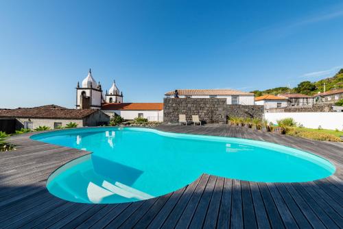 a swimming pool on a deck with a building in the background at T1 Casa das Pereiras in Calheta de Nesquim
