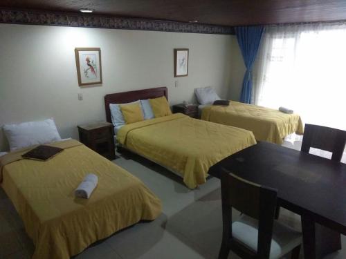 a room with two beds and a table and a dining room at Hotel Casa Rincón del Chicó in Bogotá