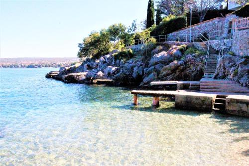 a bench sitting on the shore of a body of water at Villa Summer dream with heated pool, sauna and jacuzzi in Malinska