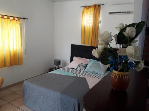 a bedroom with a bed with a vase of flowers on a table at Coralia BAYALOCATION in Sainte-Luce