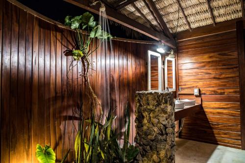 a bathroom with a wooden wall with a sink and a plant at Pousada Vayú in Icaraí