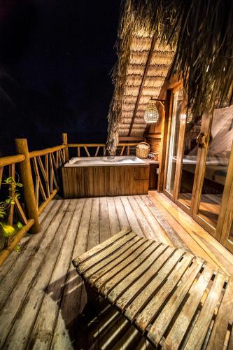 a wooden deck with a hot tub and a bench at Pousada Vayú in Icaraí