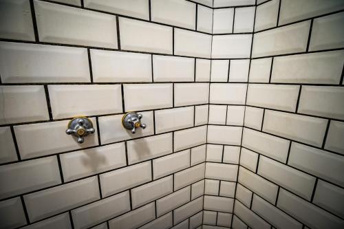 a white tiled bathroom with two faucets at Pousada Vayú in Icaraí