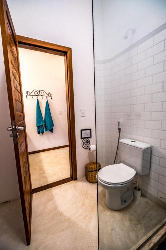 a bathroom with a toilet and a glass door at Pousada Vayú in Icaraí