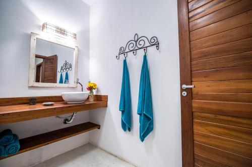 a bathroom with a sink and a mirror and a door at Pousada Vayú in Icaraí