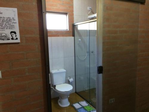 a bathroom with a toilet and a glass shower at Oficina da Passagem in São Bento do Sapucaí