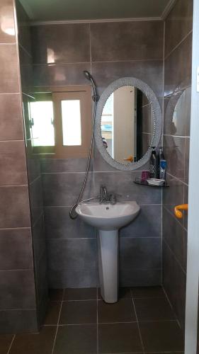 ein Bad mit einem Waschbecken und einem Spiegel in der Unterkunft Kangguan Guesthouse in Tongyeong