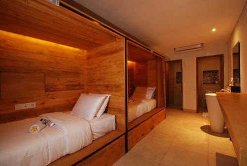 a bedroom with two beds with wooden walls at DBeds Kuta Beach By Destiny Hospitality in Kuta