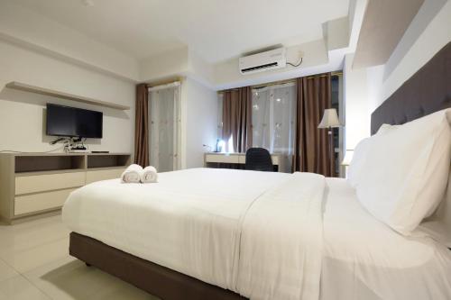 a hotel room with a large white bed and a television at Best Price Spacious Studio Apartment at H Residence near MT Haryono By Travelio in Jakarta