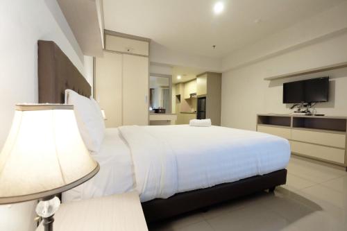 a bedroom with a large white bed and a lamp at Best Price Spacious Studio Apartment at H Residence near MT Haryono By Travelio in Jakarta