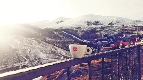 a coffee cup sitting on the ledge of a balcony at Villa Winterfell Popova Shapka in Popova Shapka