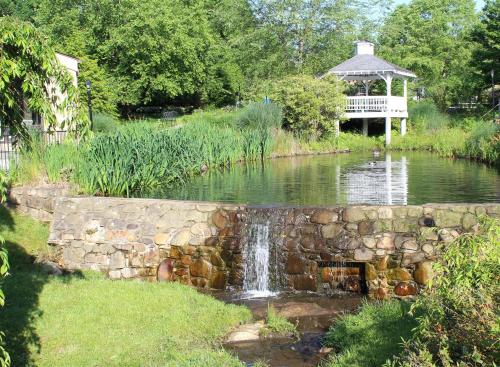 a pond with a stone wall and a gazebo at Meadowbrook Inn in Blowing Rock