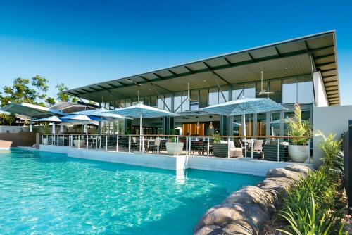 a house with a swimming pool with blue umbrellas at Mindil Beach Casino Resort in Darwin