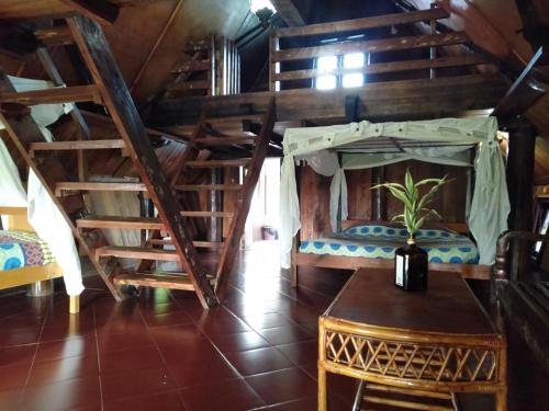 a room with a bed and a table and stairs at Bagus Bay Homestay in Tuk Tuk