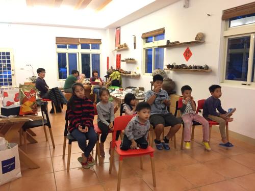 eine Gruppe von Kindern, die in einem Zimmer auf Stühlen sitzen in der Unterkunft The house behind stream in Dahu