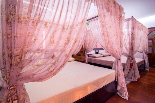 um quarto com 2 camas e cortinas cor-de-rosa em Napakarn Homestay em Chiang Rai
