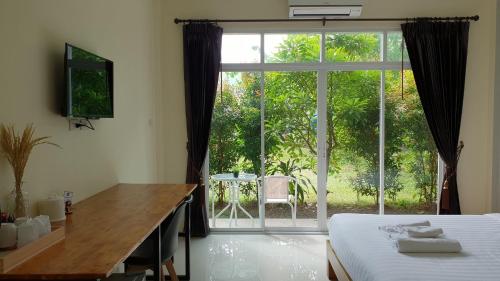 a bedroom with a bed and a desk and a large window at Snooze Inn Phuket in Ban Pa Khlok