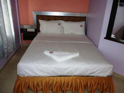 a bed with a white sheets and pillows on it at Abimon Residency Kollur in Kollūru