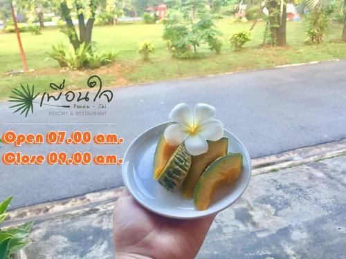 uma pessoa segurando um prato de comida com uma flor nele em Pueanjai Resort and Restaurant em Chumphon