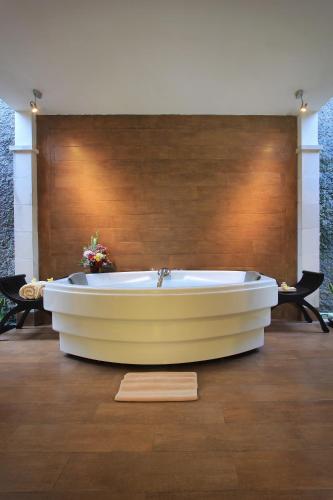 a bath tub in a room with a wooden floor at The Lagoon Bali Pool Hotel and Suites in Legian