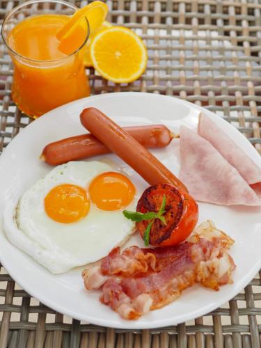 um prato de comida de pequeno-almoço com ovos, salsicha e bacon em Saai Resort em Bang Saphan Noi