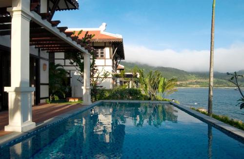 uma piscina em frente a uma casa com vista para a água em Son Tra Resort & Spa Danang em Da Nang