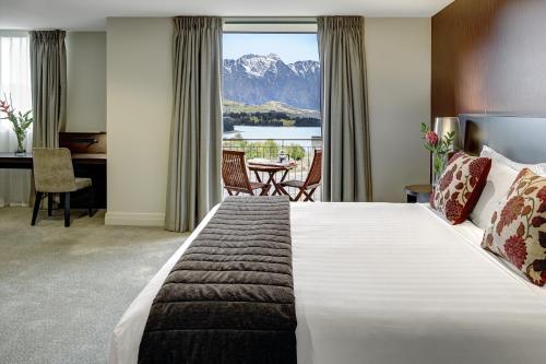 a hotel room with a large bed with a view of a mountain at Heritage Queenstown in Queenstown