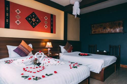 two beds in a hotel room with flowers on them at Sapa Unique Hotel in Sa Pa