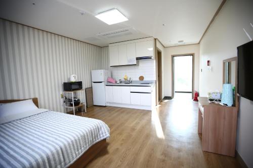 Un dormitorio con una cama y una cocina con fregadero. en Flora hostelpension, en Yeosu
