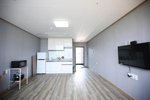 una habitación vacía con cocina y TV en la pared en Flora hostelpension, en Yeosu