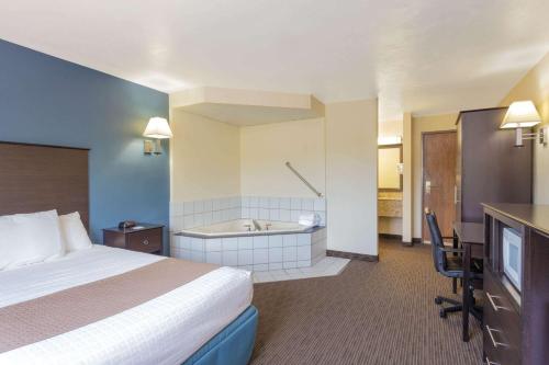 a hotel room with a bed and a bath tub at AmericInn by Wyndham Green Bay West in Green Bay