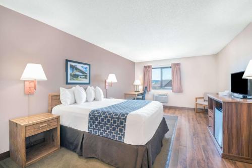 a hotel room with a bed and a flat screen tv at Days Inn by Wyndham Spearfish in Spearfish