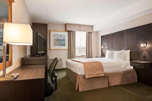 a hotel room with a bed and a desk at Days Inn by Wyndham Renfrew Conference Centre in Renfrew
