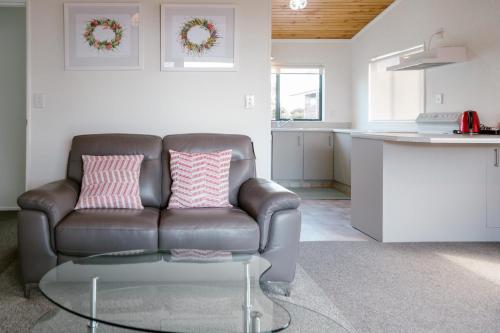 a living room with a leather couch and a glass table at Blue Marlin Apartments in Whitianga