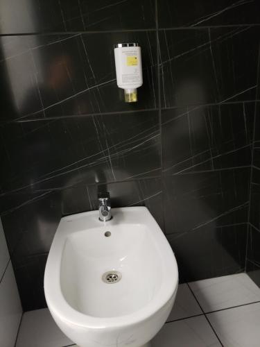 a white toilet in a black tiled bathroom at Rhombus Hotel in Luts'k