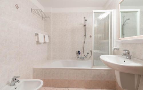 La salle de bains est pourvue d'une baignoire, d'un lavabo et d'une douche. dans l'établissement Hotel Kaserhof, à Valles