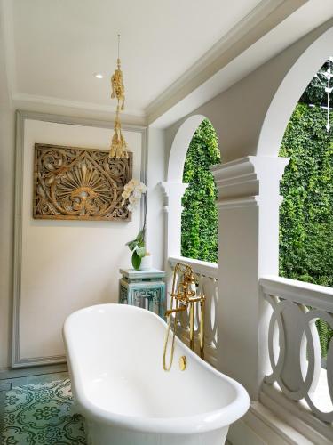 a bathroom with a white tub and two windows at The Inside House in Chiang Mai