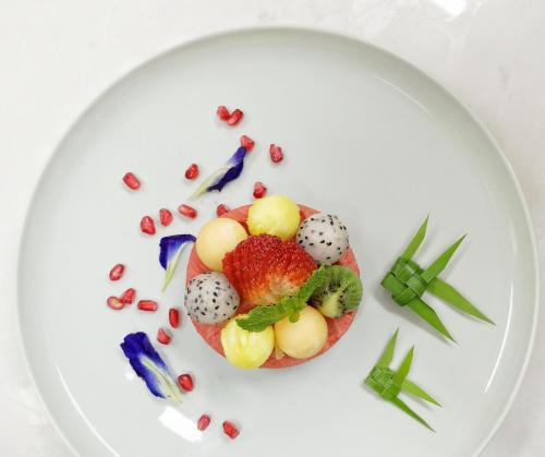 a white plate with a dessert with fruit on it at The Inside House in Chiang Mai