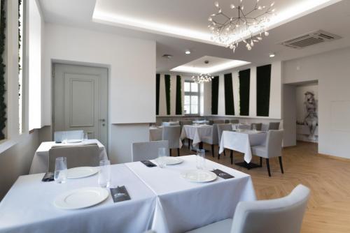 a restaurant with white tables and chairs and a chandelier at Kempen in Kępno