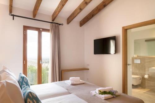 a bedroom with a bed and a tv on the wall at Angels Boutique - Turismo de interior in El Port de la Selva