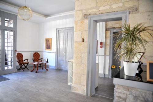 a living room with white walls and a stone fireplace at Grand Hôtel in Sainte-Foy-la-Grande
