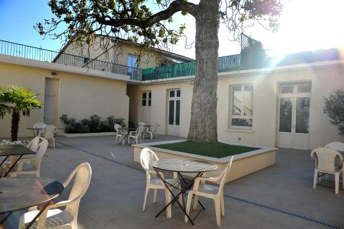 a patio with tables and chairs and a tree at Grand Hôtel in Sainte-Foy-la-Grande